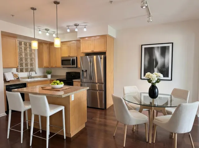 a kitchen with a dining table chairs refrigerator and microwave