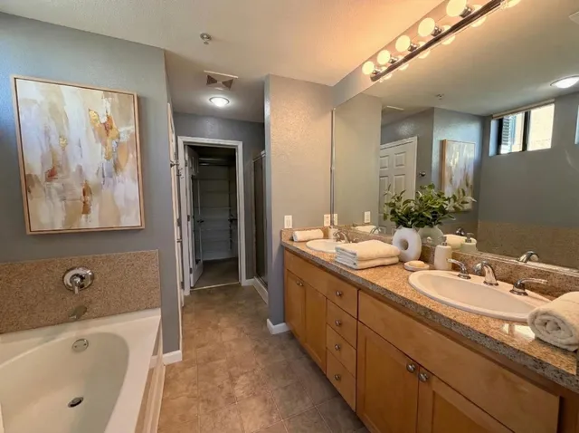 a spacious bathroom with a tub double sink and mirror