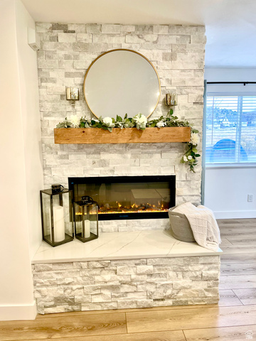 7818 North Windhover Road Eagle Mountain, UT 84005 - Photo 8 of 32 Stacked stone fireplace featuring an integrated electric firebox, a solid wood mantel, and a stone hearth