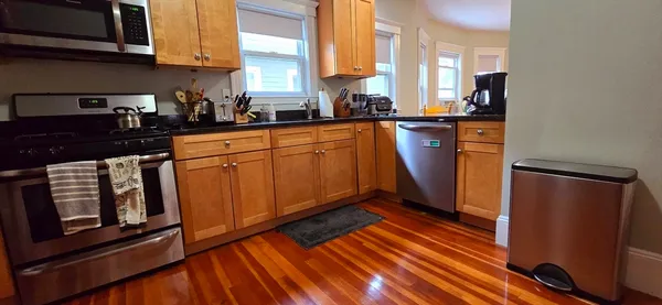 a kitchen with stainless steel appliances granite countertop a refrigerator a sink dishwasher and wooden cabinets with wooden floor