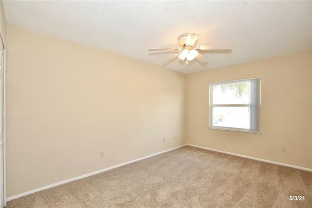 an empty room with a window and a ceiling fan