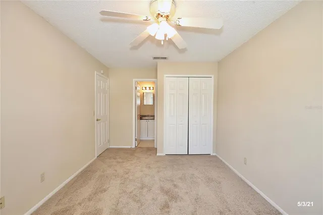 an empty room with a chandelier fan and windows