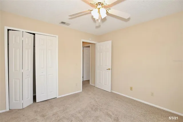 an empty room with a chandelier fan and closet area