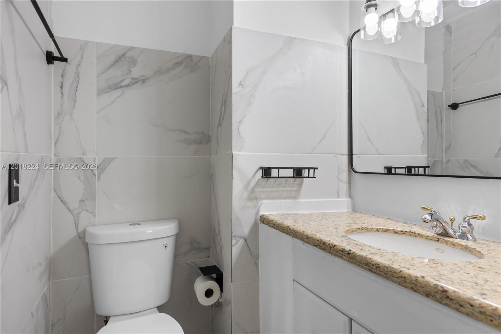 7958 Southwest 6th Street Pompano Beach, FL 33068 - Photo 39 of 57 a bathroom with a granite countertop sink a mirror and a toilet