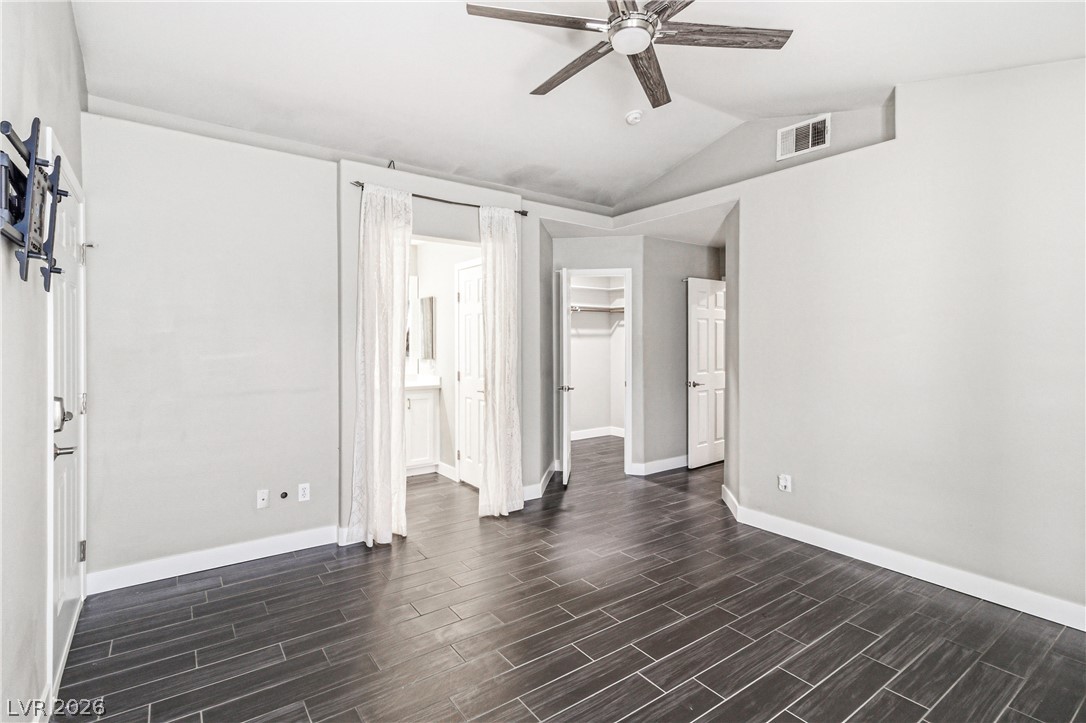 9523 Observer Street Las Vegas, NV 89123 - Photo 27 of 42 The primary bedroom offers dark plank-style flooring, a soaring vaulted ceiling, and direct access to an en-suite bath.