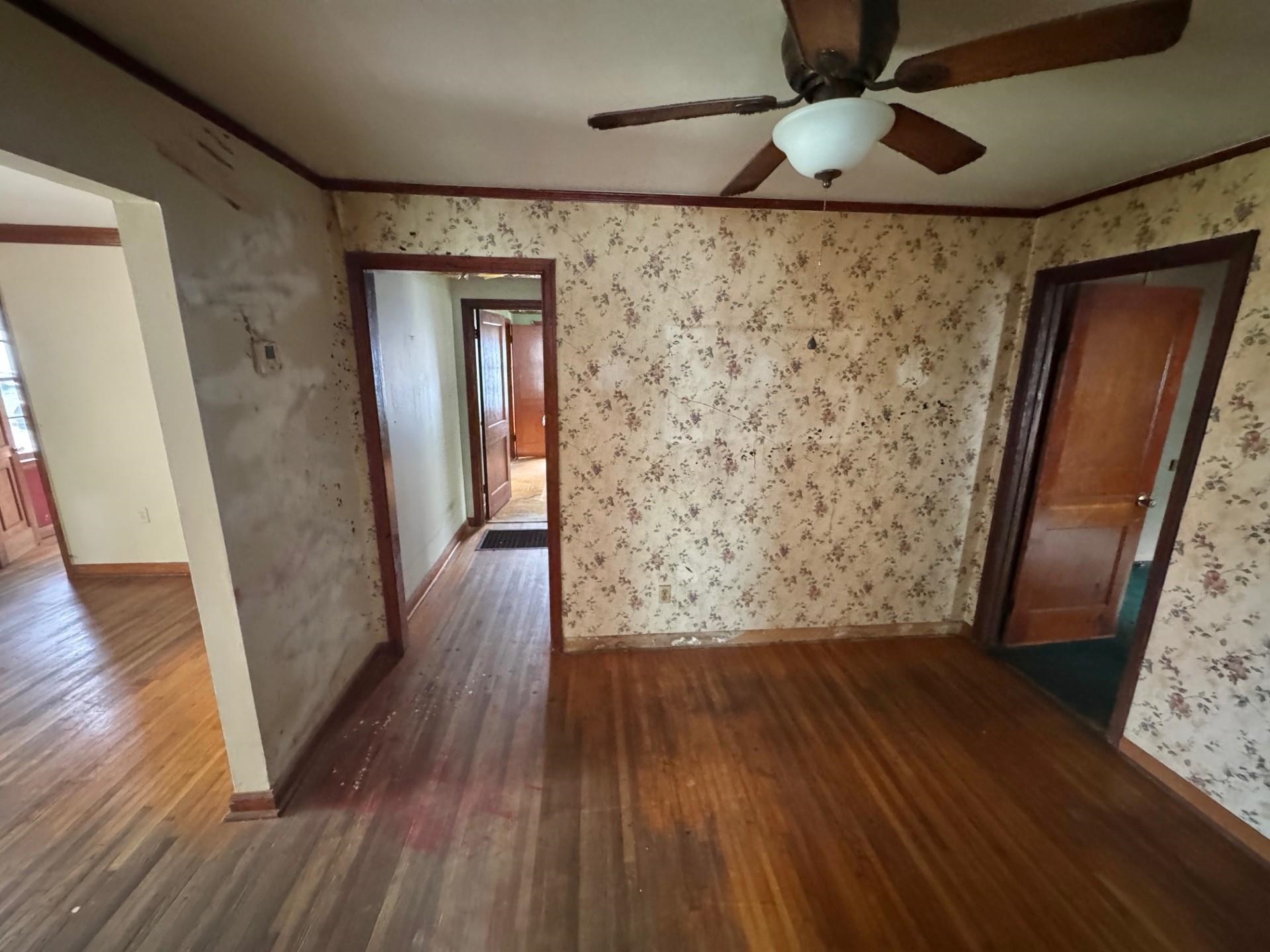 1445 Depass Road Memphis, TN 38122 - Photo 7 of 13 Unfurnished room featuring wood finished floors, crown molding, wallpapered walls, and a ceiling fan