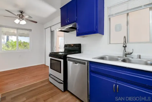 a kitchen with stainless steel appliances a sink dishwasher stove and refrigerator with wooden floor