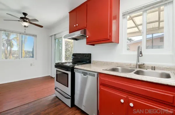 a kitchen with stainless steel appliances granite countertop a sink a stove and a wooden floor