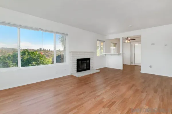 a view of empty room with wooden floor and fireplace