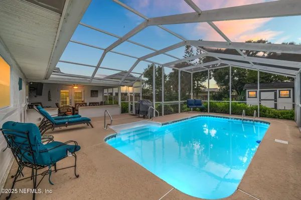 a view of a backyard with swimming pool and sitting area