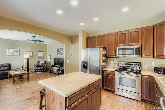 a kitchen with stainless steel appliances a stove a refrigerator a sink a oven with white cabinets and wooden floor