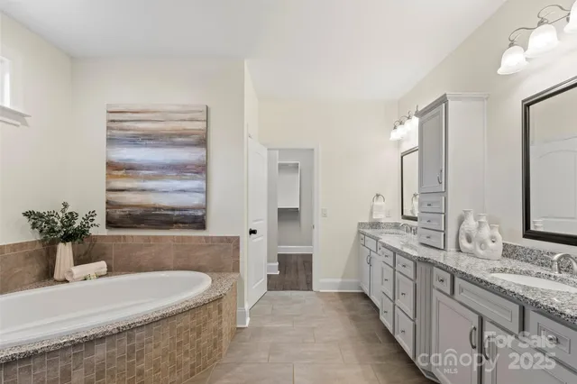 a bathroom with sink double vanity granite tub shower and a mirror
