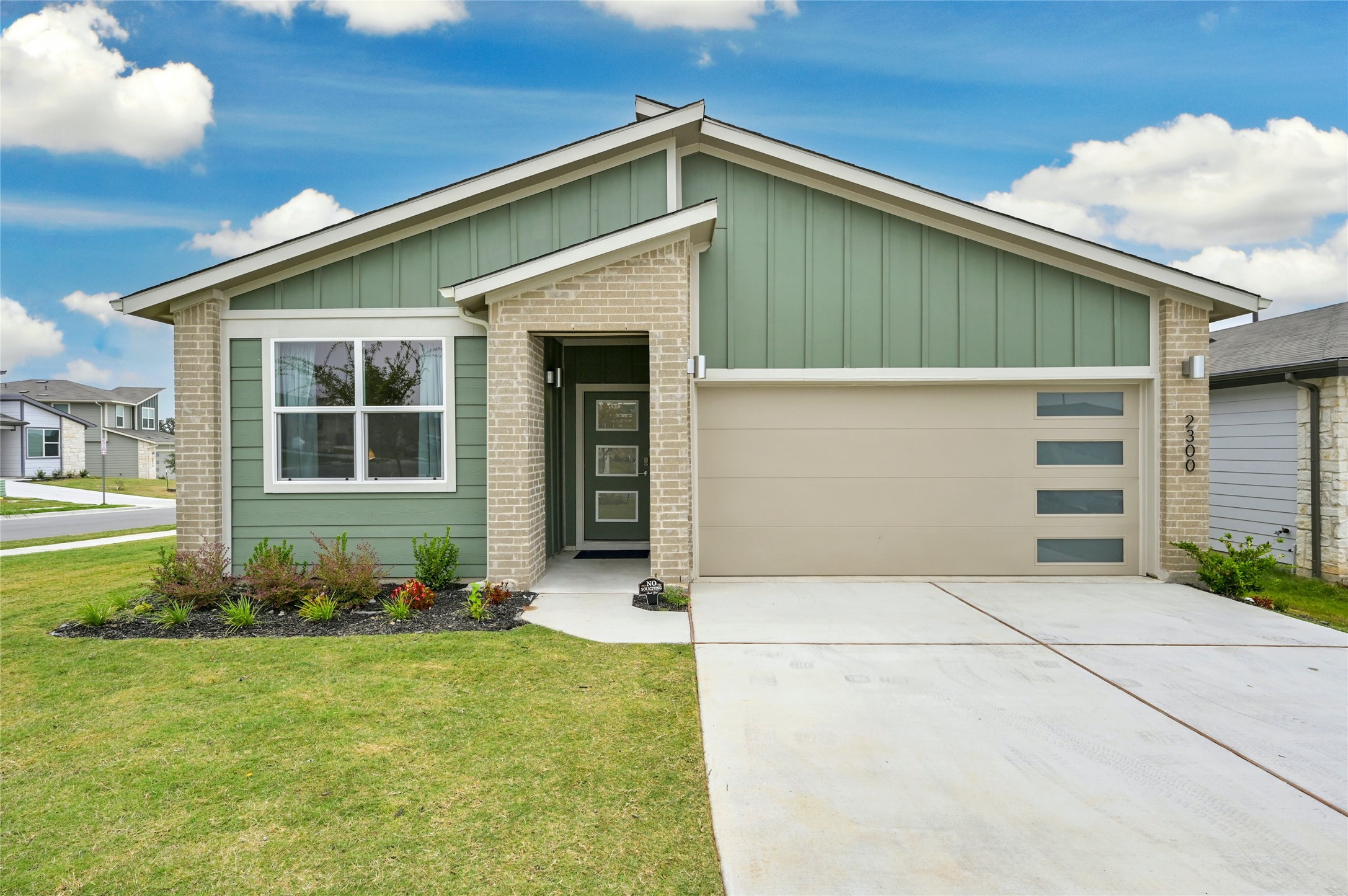2300 Ranier Court Austin, TX 78754 - Photo 1 of 24 View of front facade with a garage, driveway, board and batten siding, and brick siding