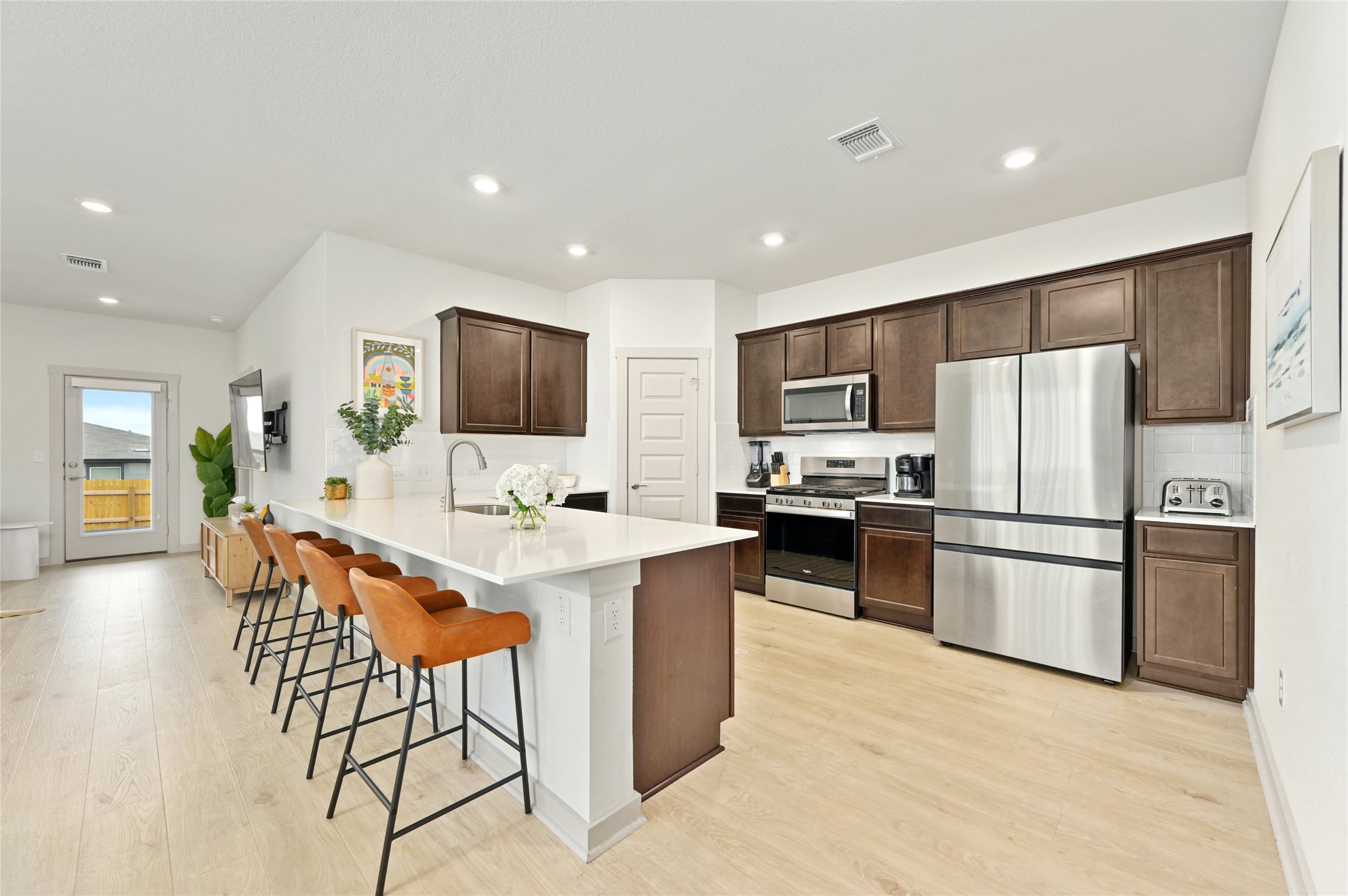 2300 Ranier Court Austin, TX 78754 - Photo 9 of 24 Kitchen featuring a peninsula, stainless steel appliances, dark wood finish cabinets, a breakfast bar area, and light wood-type flooring
