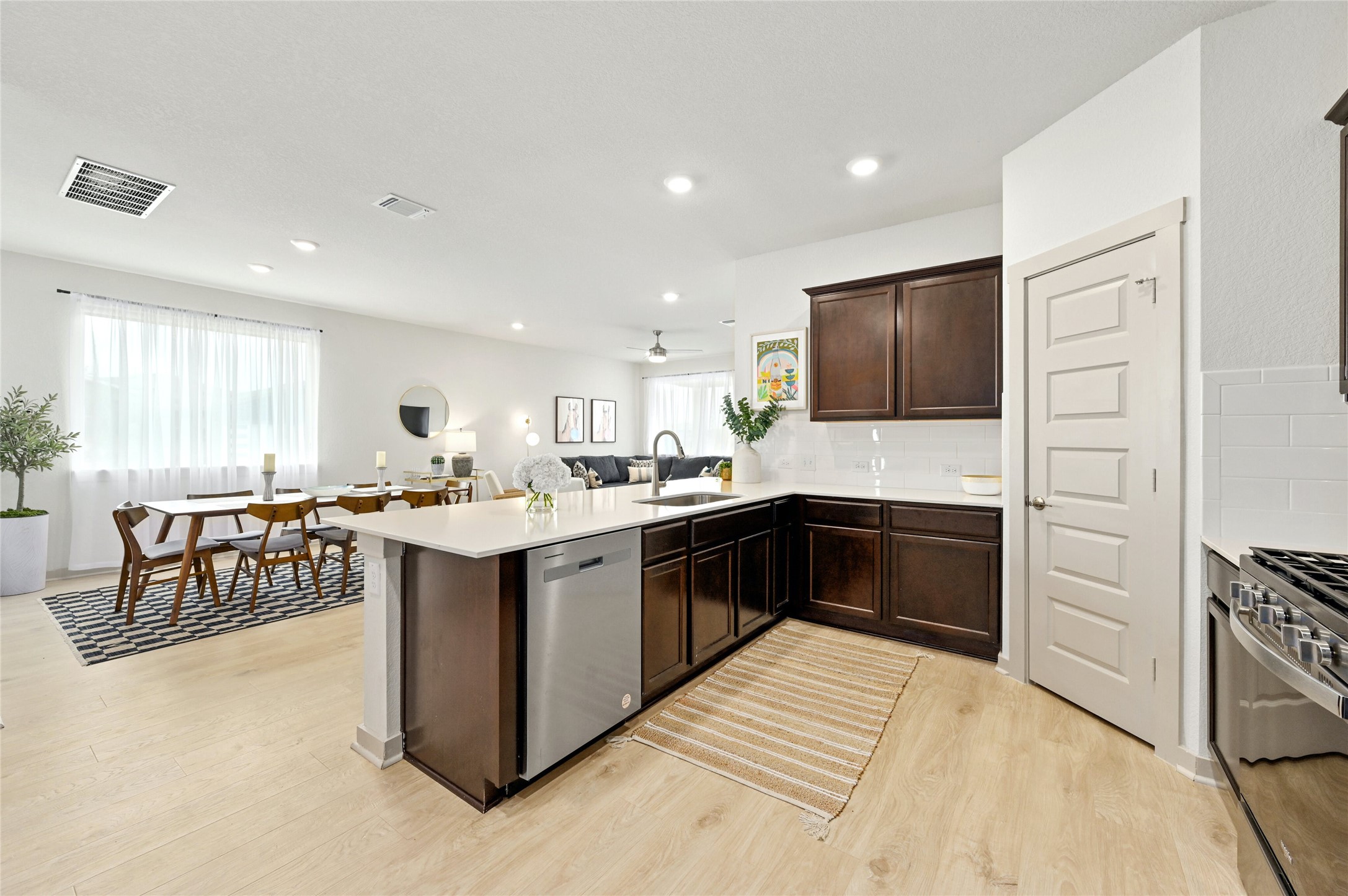 2300 Ranier Court Austin, TX 78754 - Photo 10 of 24 Kitchen with a peninsula, dishwasher, light wood-style floors, dark wood finish cabinets, and decorative backsplash