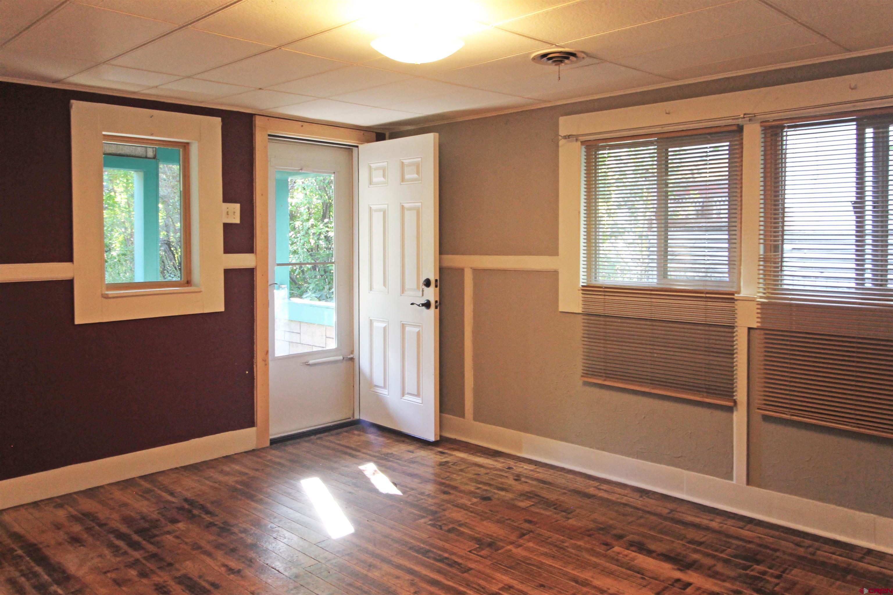 304 South Walnut Street Mancos, CO 81328 - Photo 3 of 31 an empty room with wooden floor and windows
