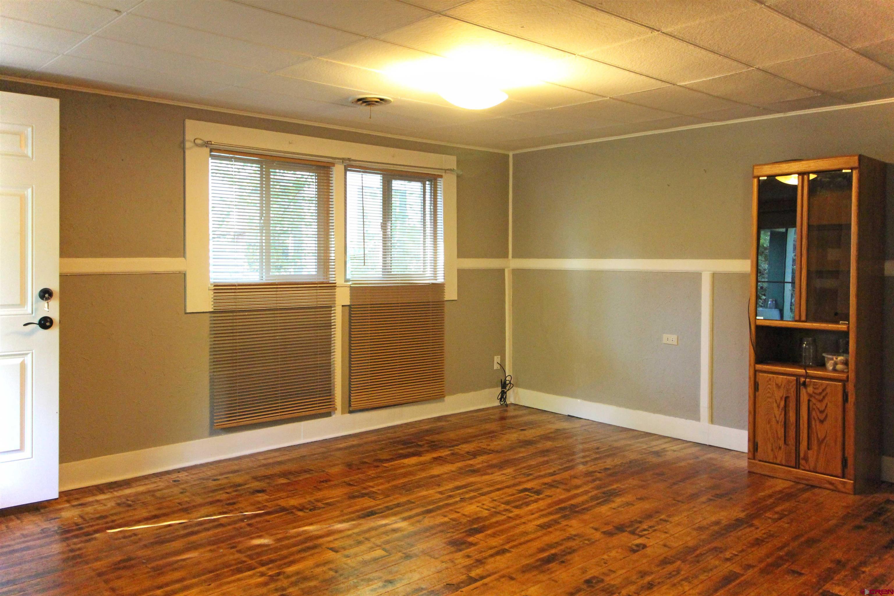 304 South Walnut Street Mancos, CO 81328 - Photo 5 of 31 an empty room with wooden floor and windows