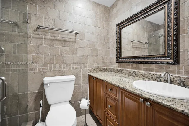 a bathroom with a granite countertop toilet sink and mirror