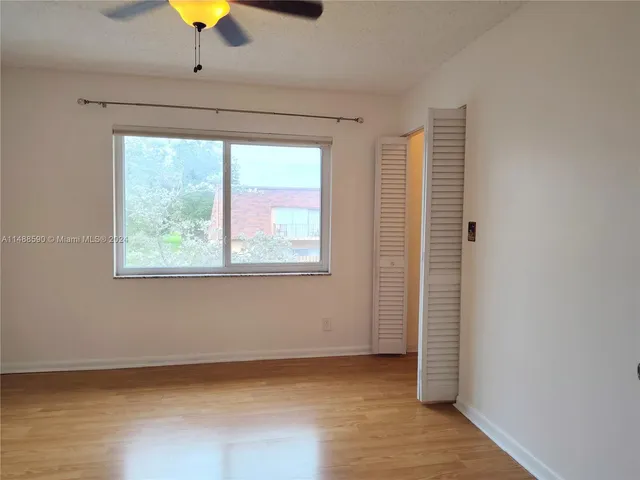 an empty room with a window and a ceiling fan