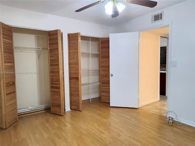 an empty room with wooden floor closet and chandelier