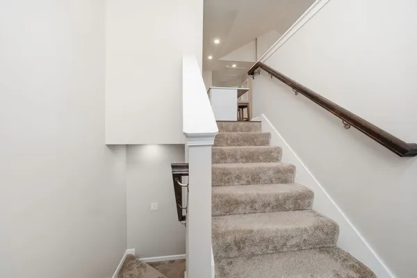 a view of staircase with white walls and white door