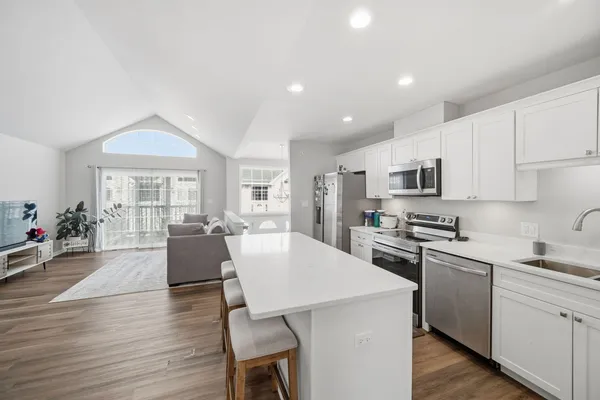 a living room with stainless steel appliances furniture a dining table and kitchen view