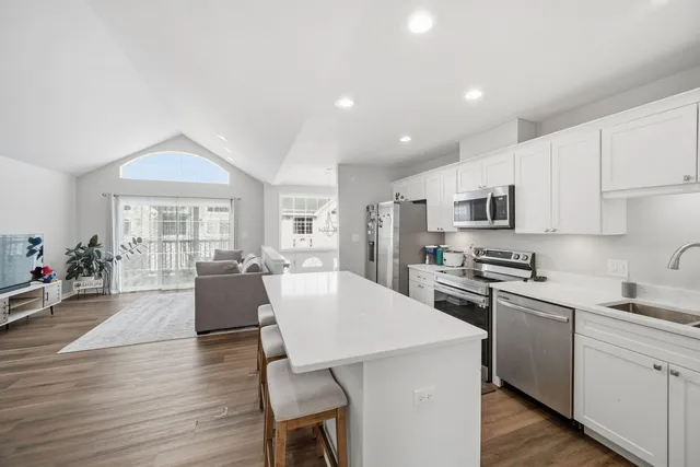 a living room with stainless steel appliances furniture a dining table and kitchen view