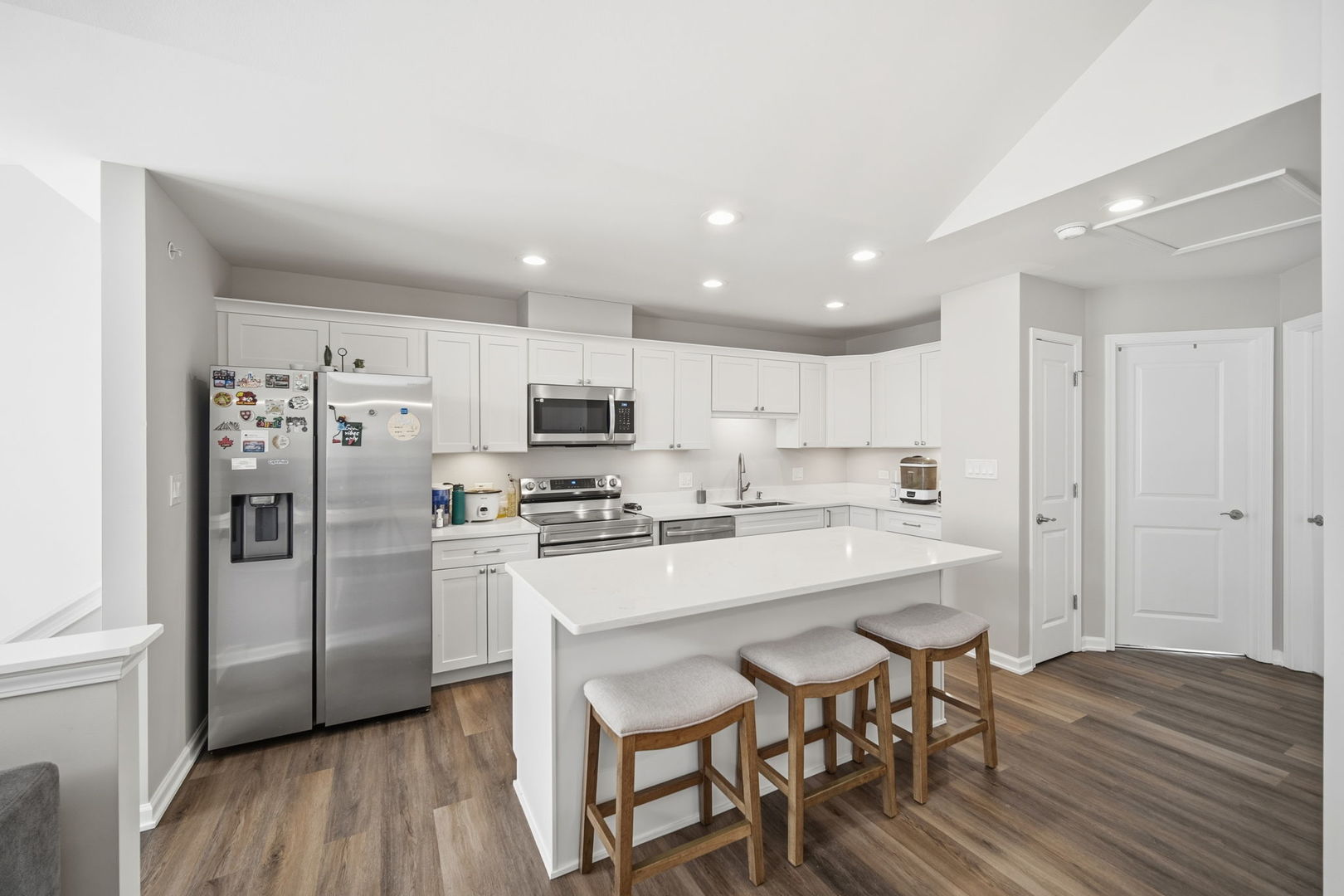 7214 Farmstead Lane Hanover Park, IL 60133 - Photo 6 of 30 a kitchen with stainless steel appliances a refrigerator a stove top oven a sink dishwasher and white cabinets with wooden floor