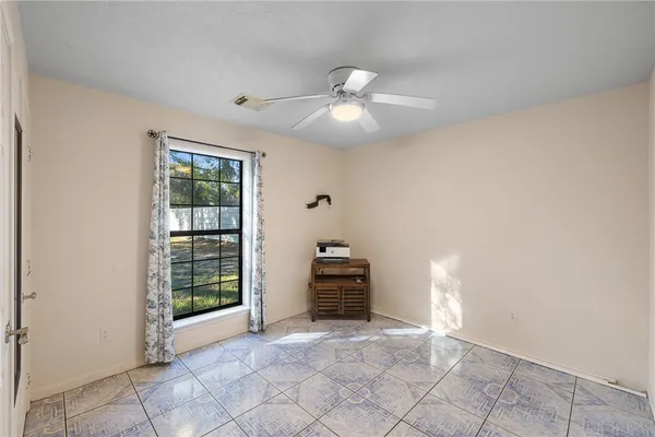 en empty room with windows and ceiling fan