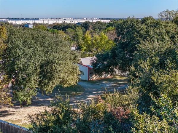 an aerial view of a residential houses with outdoor space and trees