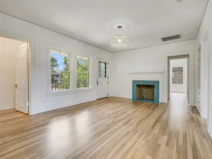 an empty room with wooden floor fireplace and windows