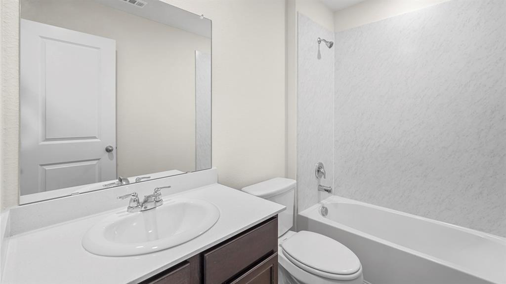 1953 Freeman Street Tyler, TX 75704 - Photo 31 of 32 Contemporary bathroom featuring a dark wood-finish vanity with an integrated sink, polished chrome faucet, and a large frameless mirror