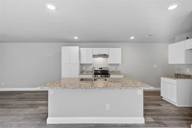 a view of kitchen island a sink wooden floor wooden floor and kitchen island
