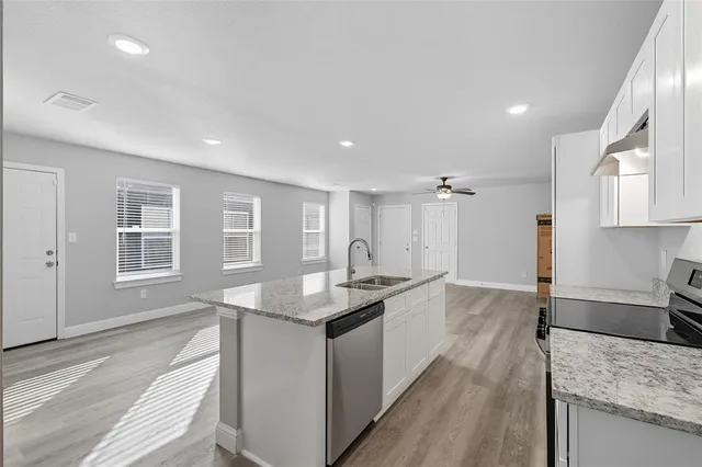 a large kitchen with kitchen island a large counter top space a sink stainless steel appliances and windows