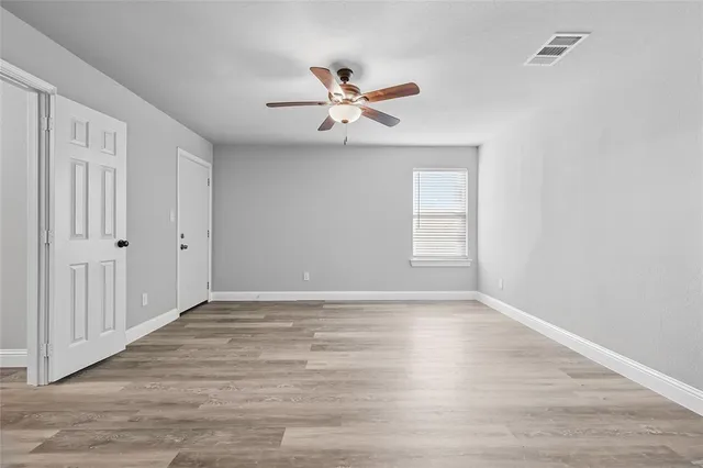 a view of empty room with wooden floor and fan