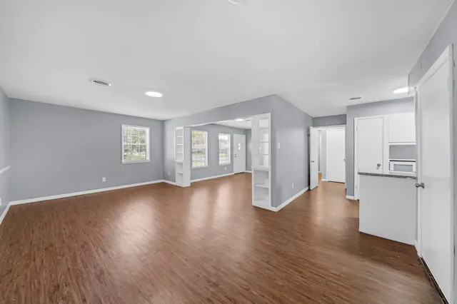 a view of an empty room with a window and wooden floor