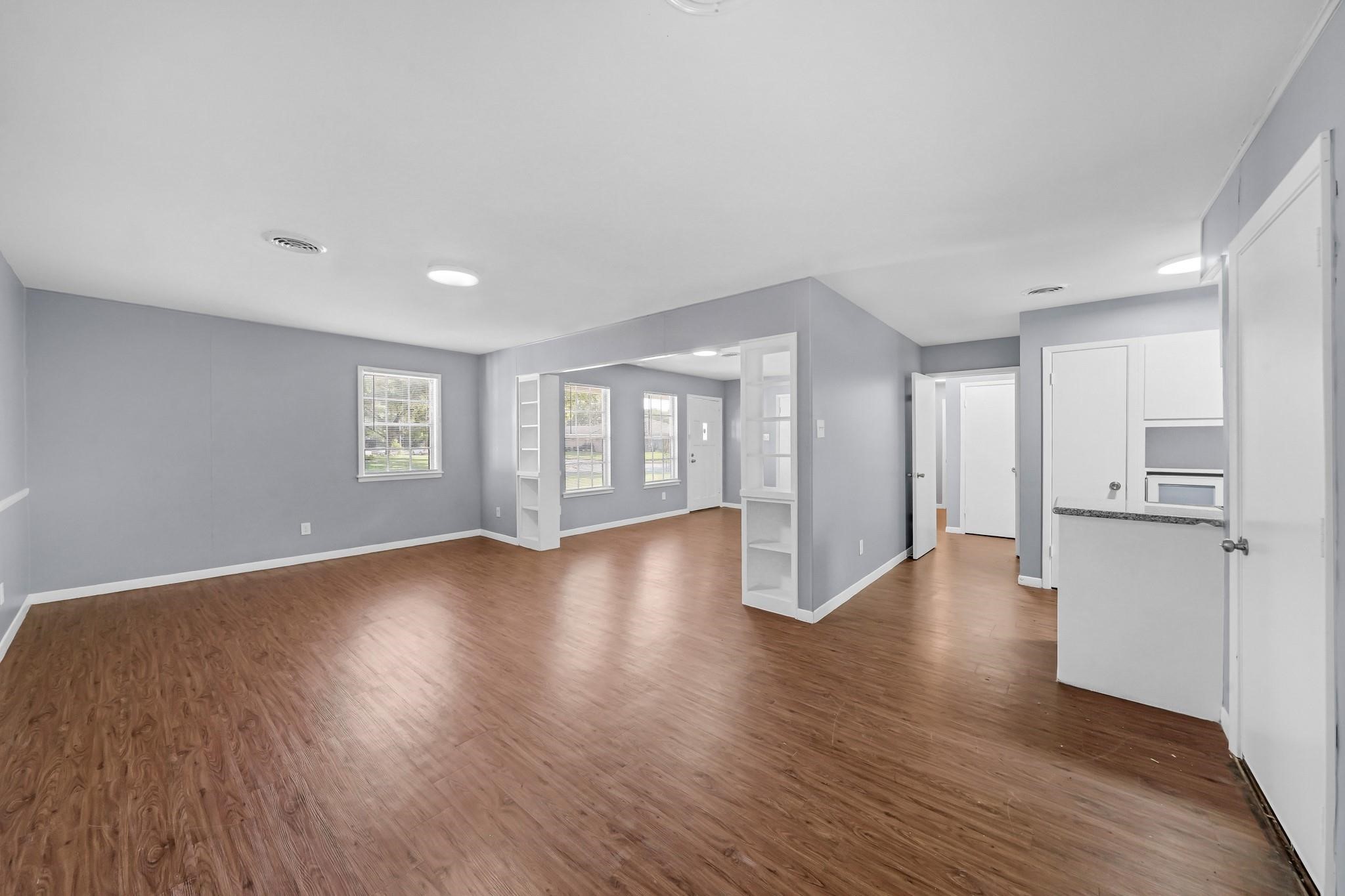 a view of an empty room with a window and wooden floor