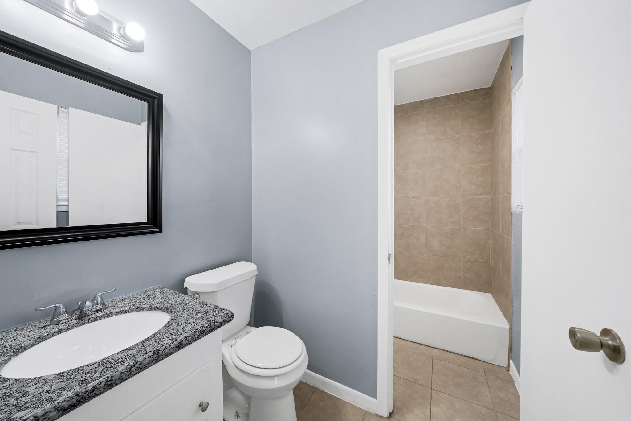 11202 Waxwing Street Houston, TX 77035 - Photo 11 of 19 a bathroom with a granite countertop sink toilet and mirror