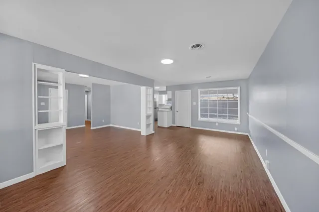 a view of an empty room with a window and wooden floor