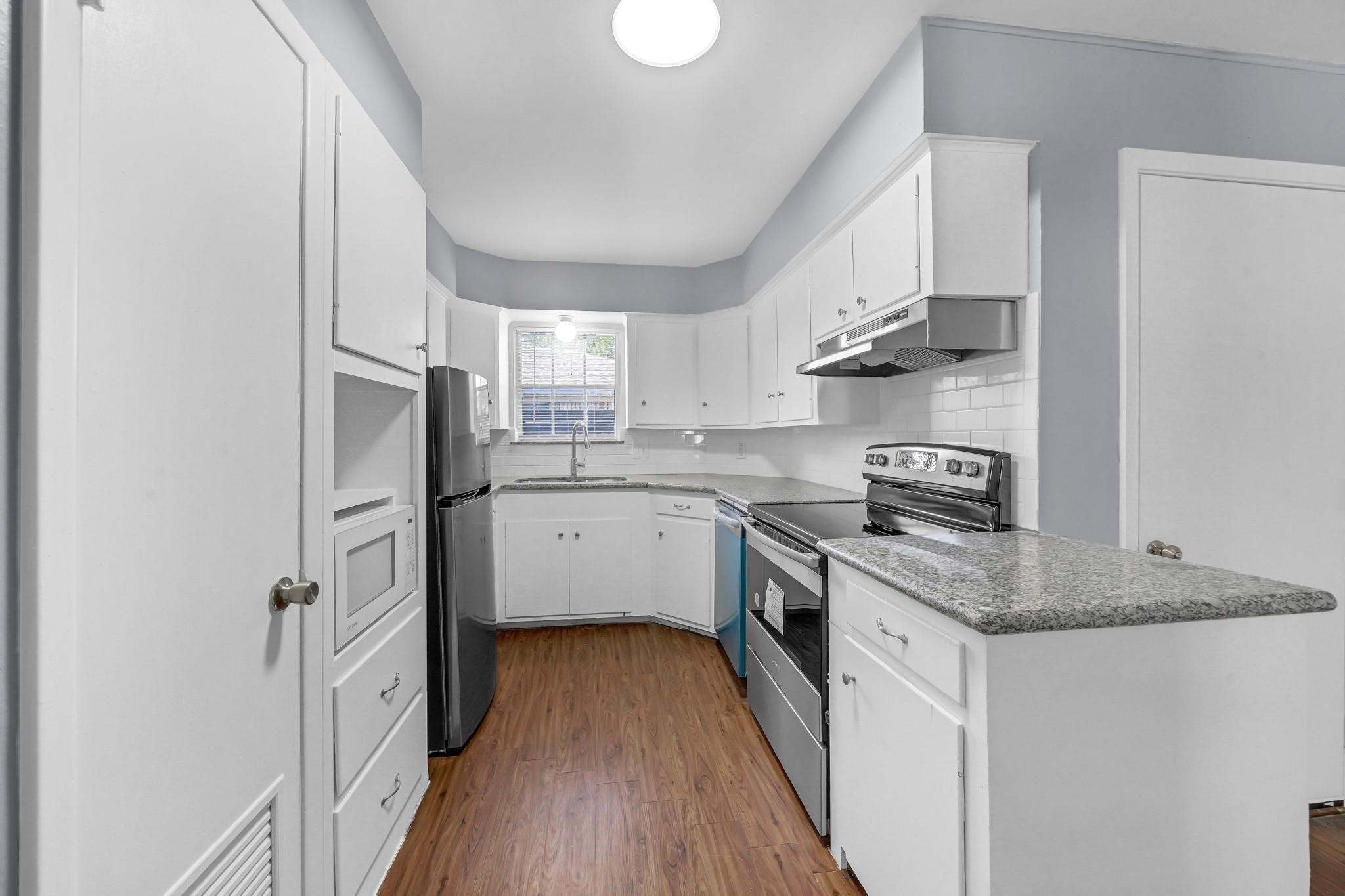 11202 Waxwing Street Houston, TX 77035 - Photo 4 of 19 a kitchen with stainless steel appliances granite countertop a refrigerator a sink dishwasher a stove and white countertops with wooden floor