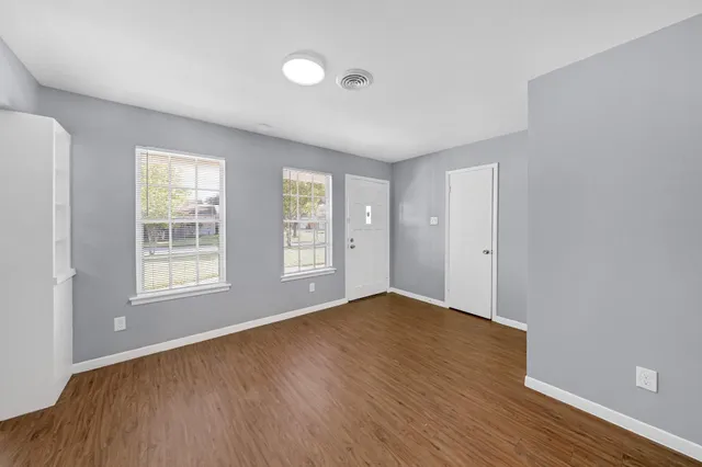 an empty room with wooden floor and windows
