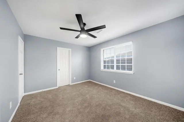 a view of a big room with windows and ceiling fan