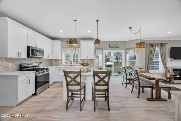 a kitchen with stainless steel appliances granite countertop a table chairs sink and cabinets