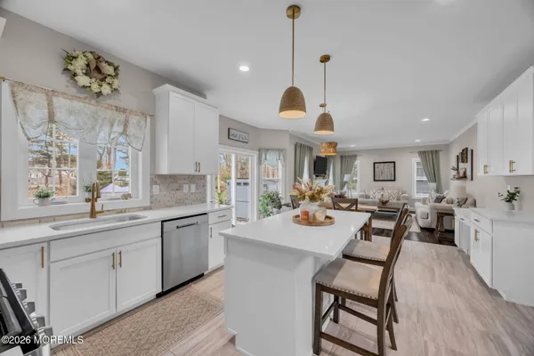 a very nice looking dining room with kitchen island furniture a chandelier a large window and wooden floor