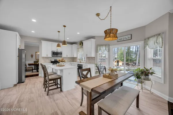 a dining room with stainless steel appliances kitchen island granite countertop a table chairs and a refrigerator