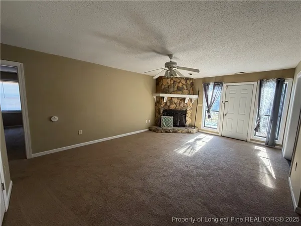 a view of empty room with fireplace and windows