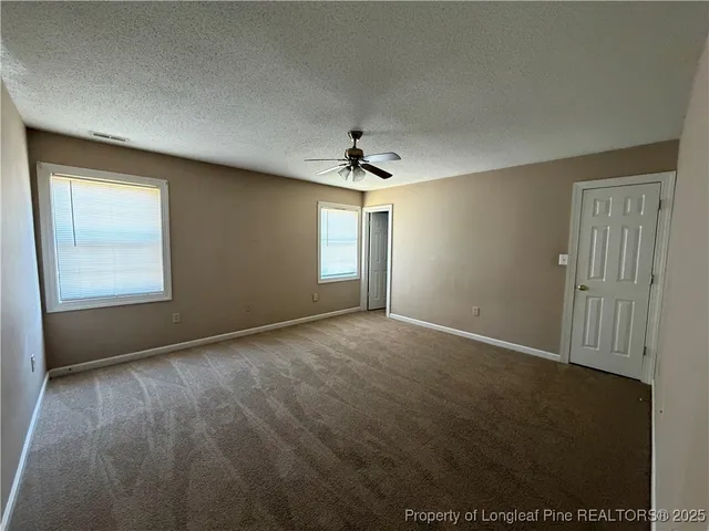 an empty room with windows and chandelier fan
