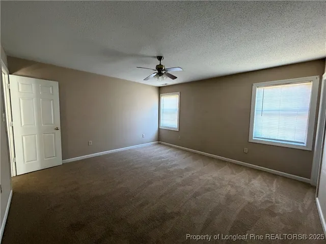 an empty room with windows and chandelier fan