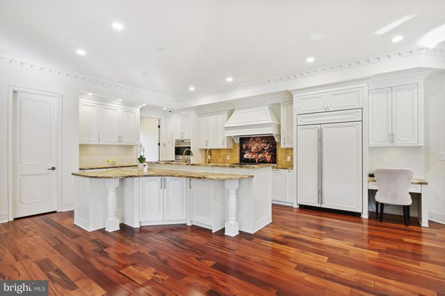 a kitchen with stainless steel appliances granite countertop a refrigerator a stove top oven a sink dishwasher and white cabinets with wooden floor