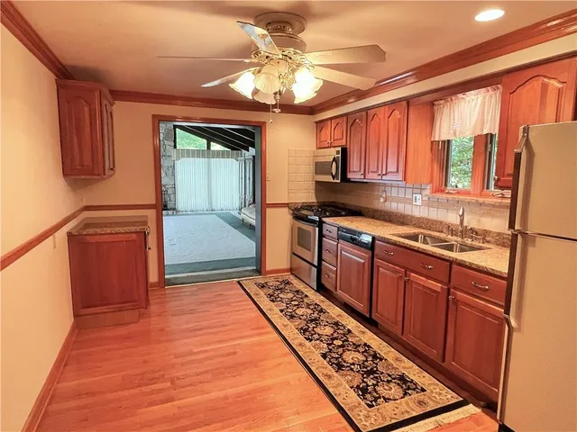 a kitchen with stainless steel appliances granite countertop a stove a sink dishwasher and a refrigerator with wooden cabinets